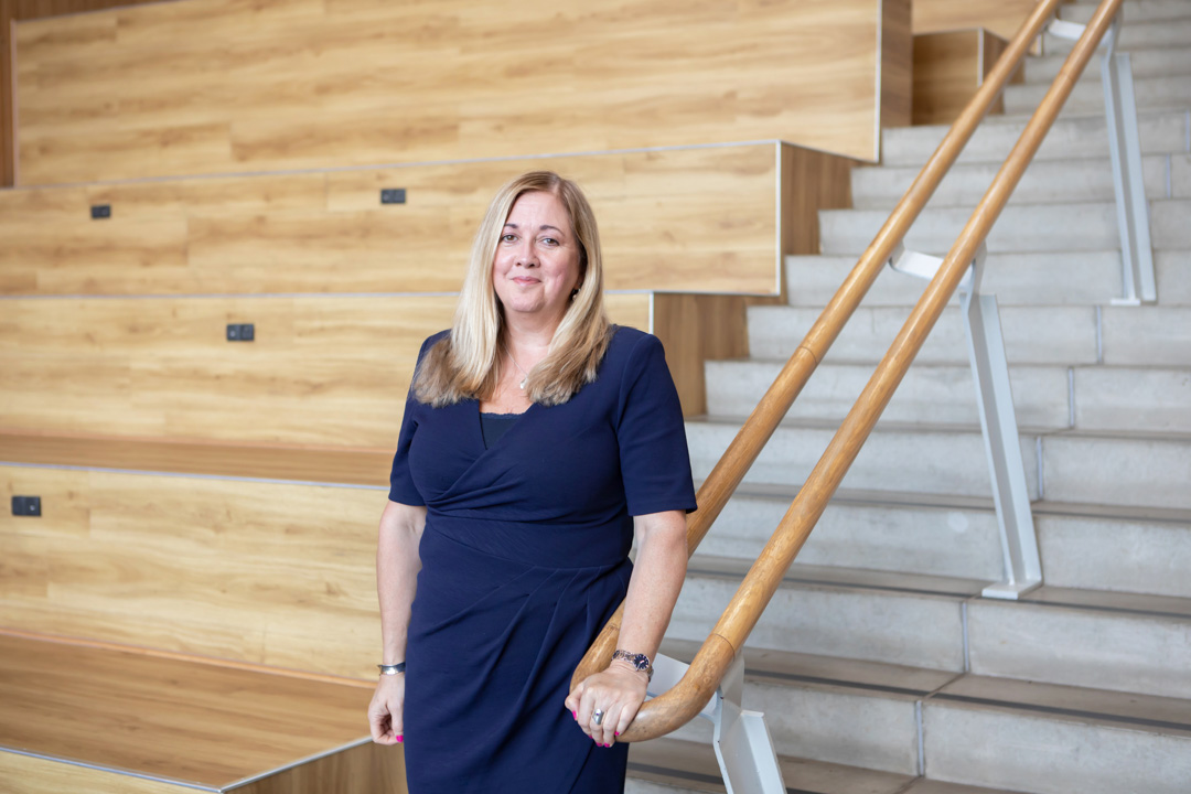 Jeanette Evans, Vice Principal of Operations at Glasgow Kelvin College, standing beside a staircase in the college’s modern lecture space