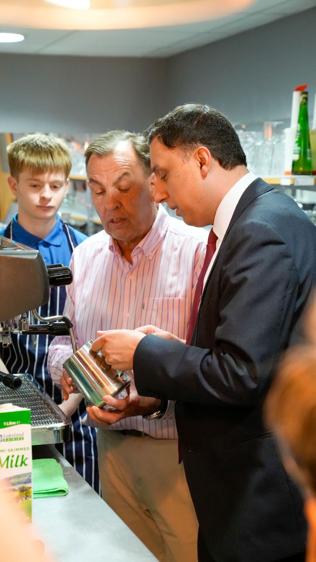 Anas Sarwar observing coffee-making skills with hospitality students in barista training session.