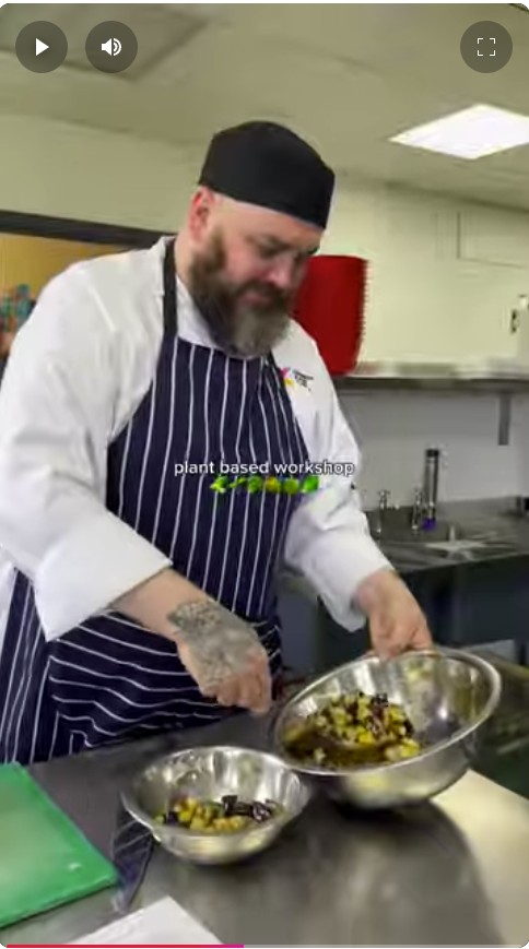 Chef at Glasgow Kelvin College preparing a plant-based dish during a Forward Food workshop, mixing ingredients in a stainless steel bowl