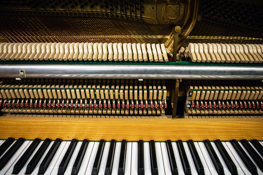 A close-up view of an upright piano’s inner mechanics, showing hammers, strings, and the keyboard.