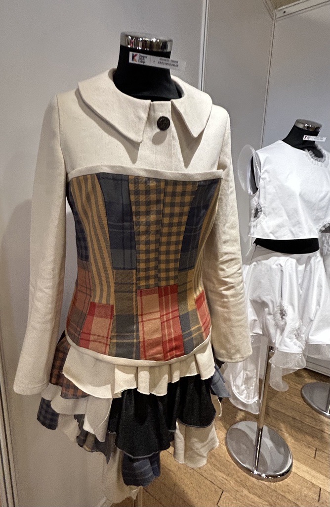 A cream jacket with a colourful tartan patchwork bodice and layered ruffle skirt, part of an upcycled fashion design on display at Craftex 2025