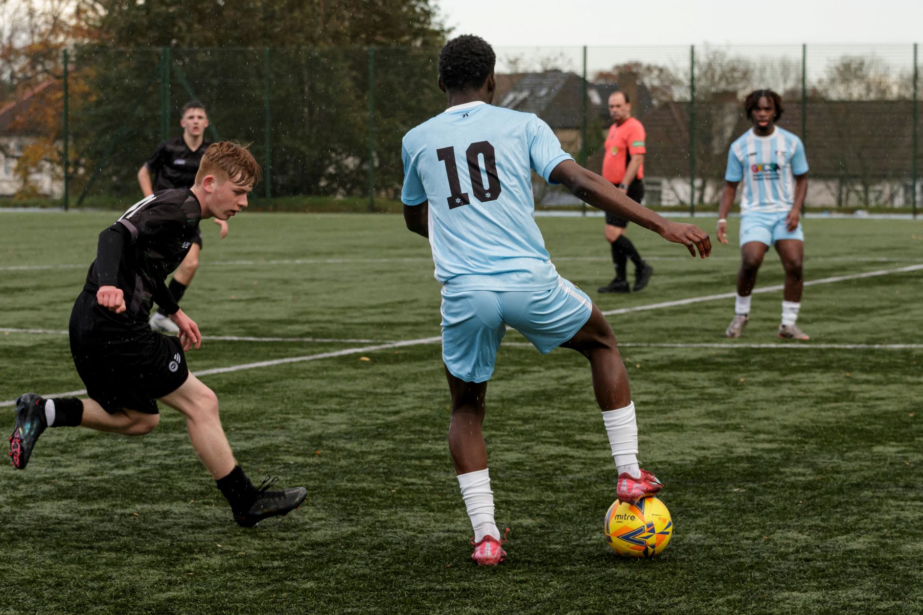Glasgow Kelvin College football player in light blue kit controlling the ball during a competitive match on an outdoor pitch.