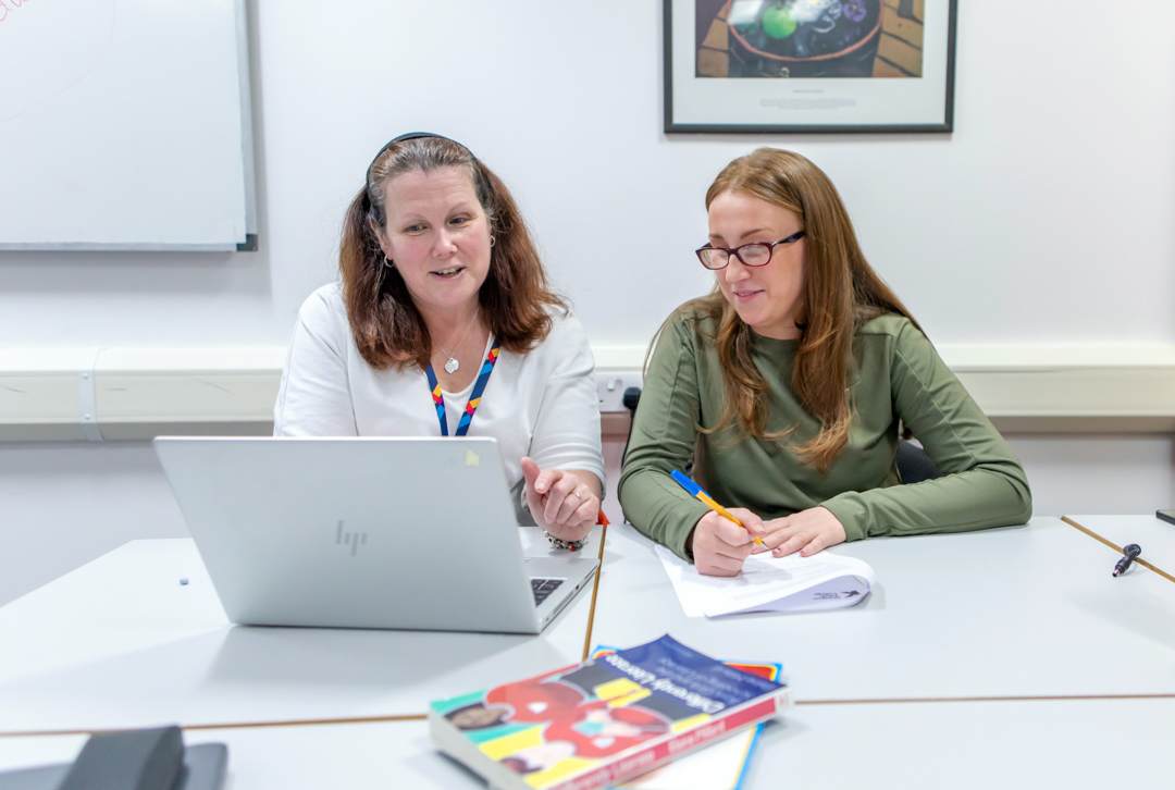 A Glasgow Kelvin College lecturer offering personalised support, guiding a student through coursework in a relaxed, friendly atmosphere.